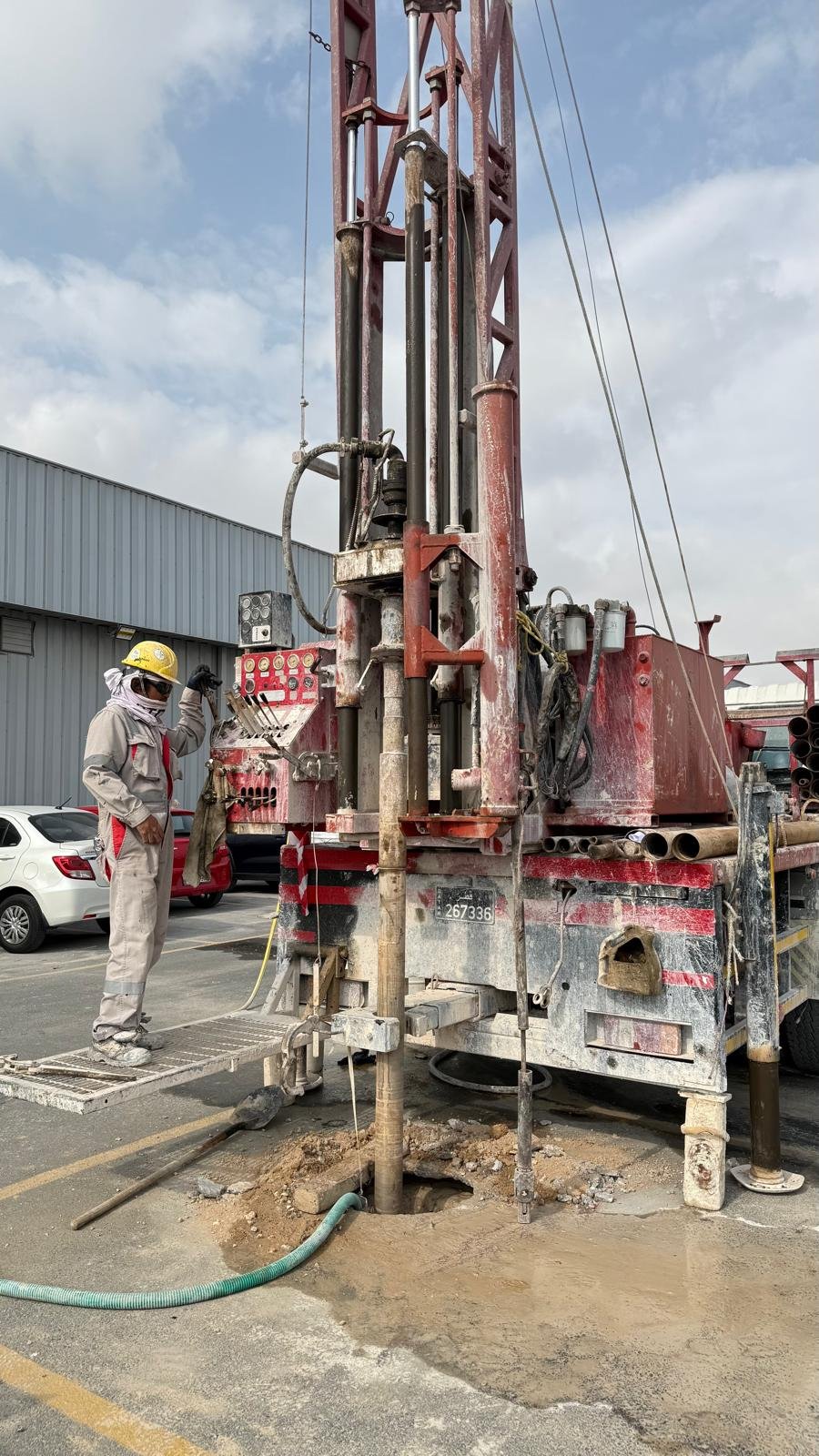 A geotechnical engineer operating a truck-mounted drilling rig conducting soil investigation and borehole drilling on an asphalt parking lot.
