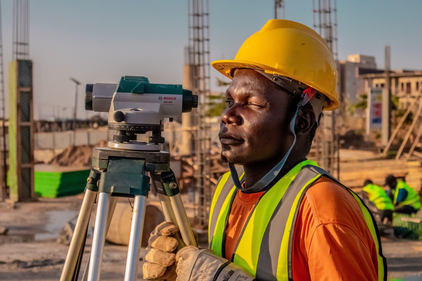 Surveyor using a GNSS receiver beside a layered GIS map on screen