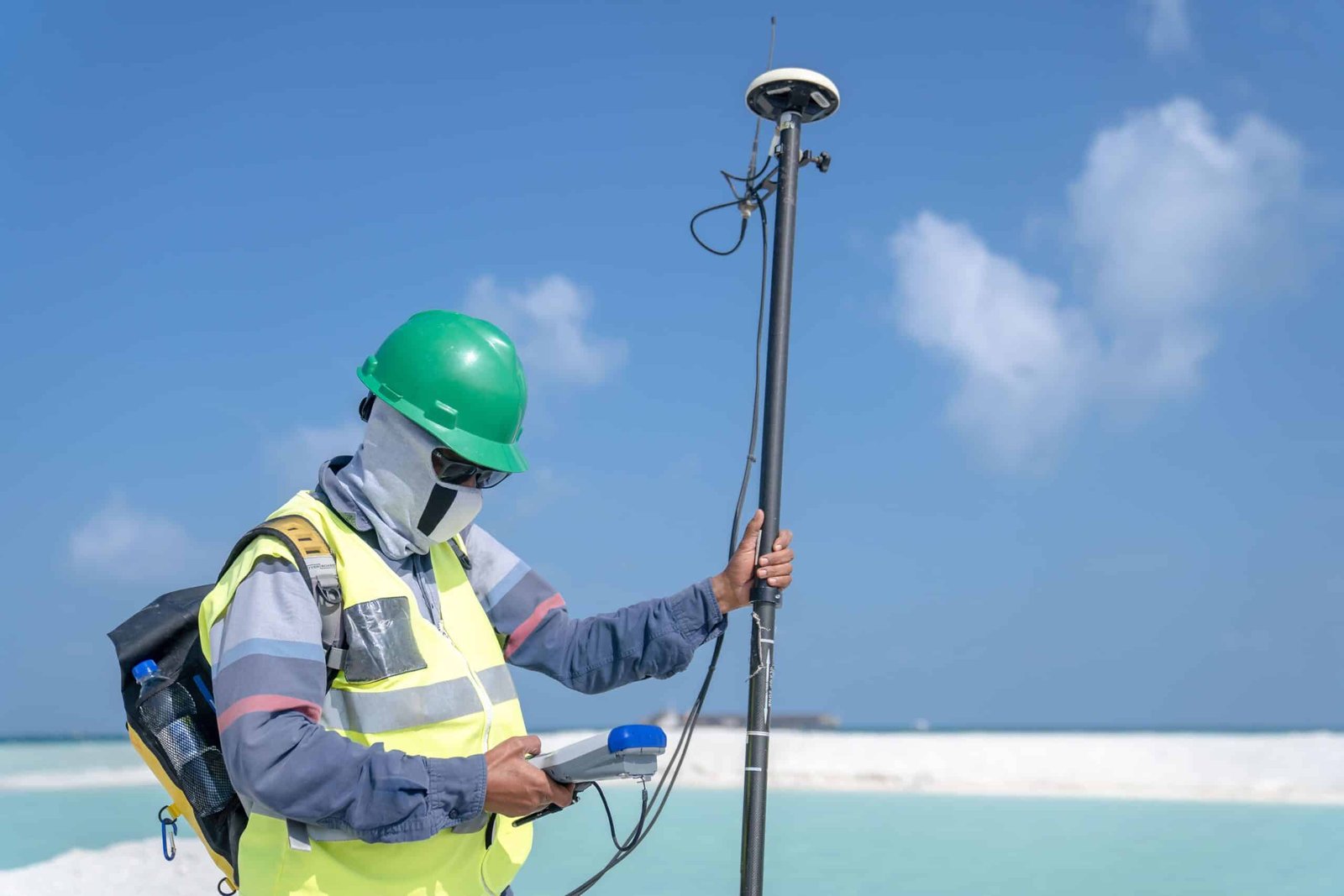 Surveyor using a total station to mark a property boundary line on a plot of land