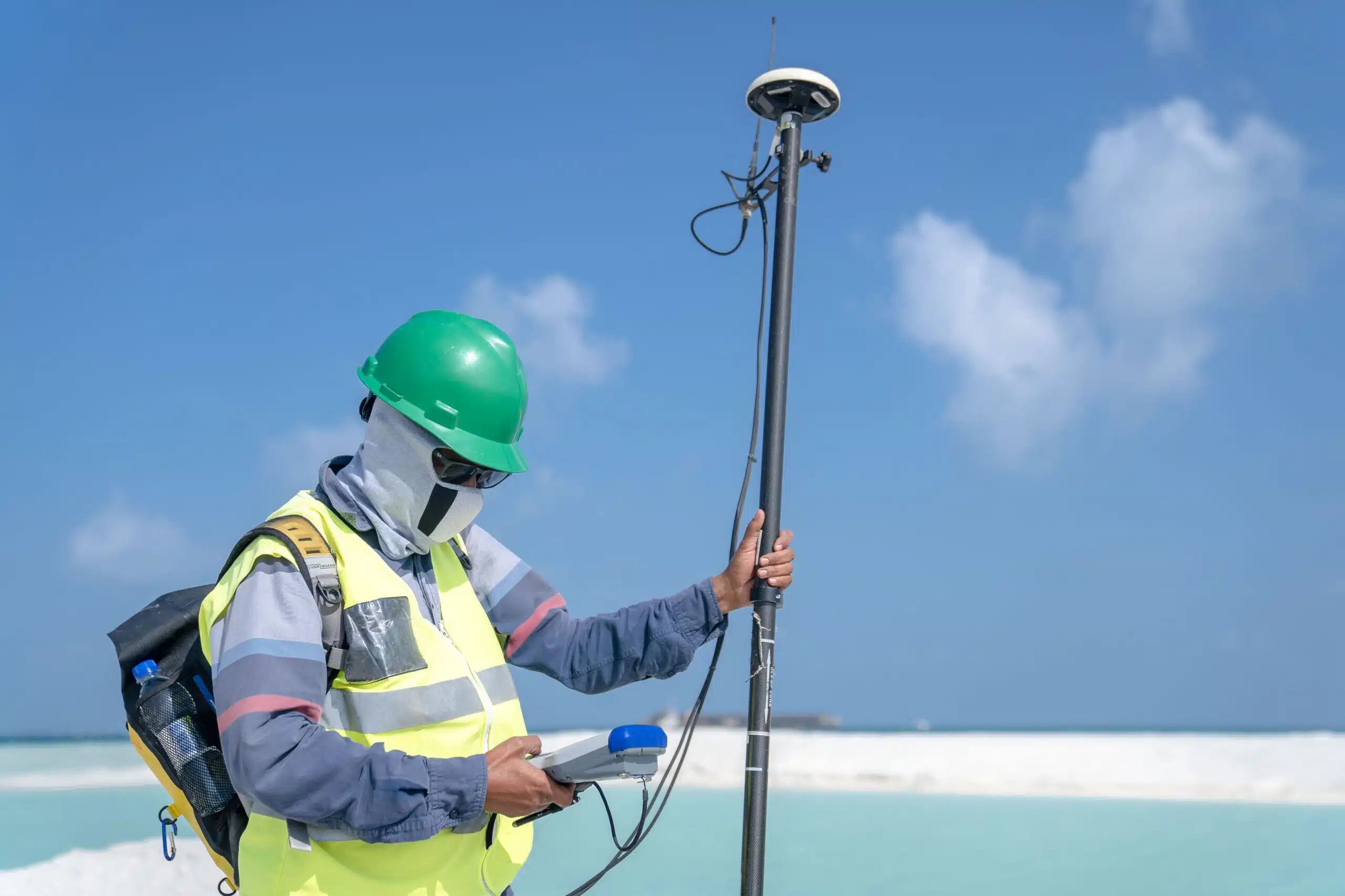 Surveyor using a total station to mark a property boundary line on a plot of land